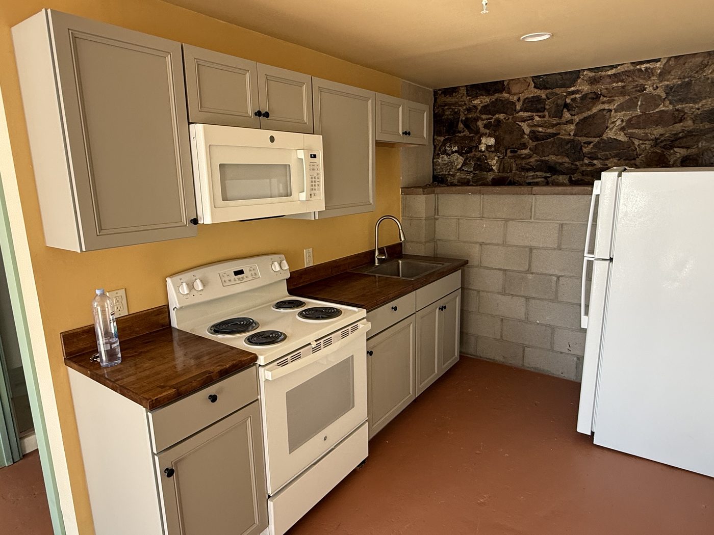 The Crown kitchen — gray cabinets, butcher-block counter, and yellow wall