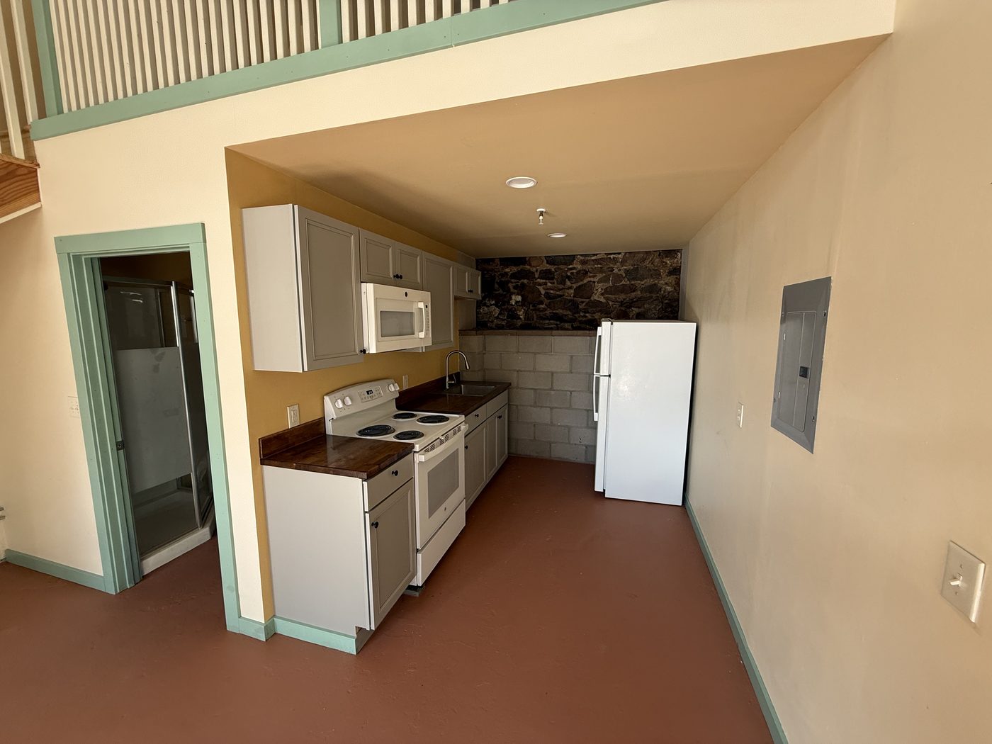 The Crown medium loft — kitchen with butcher-block counters, loft underside, and doorway toward the bath