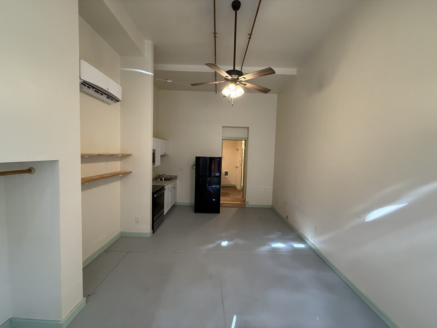 The Jewel studio — living area with kitchen alcove and stone wall (furnishing in progress)